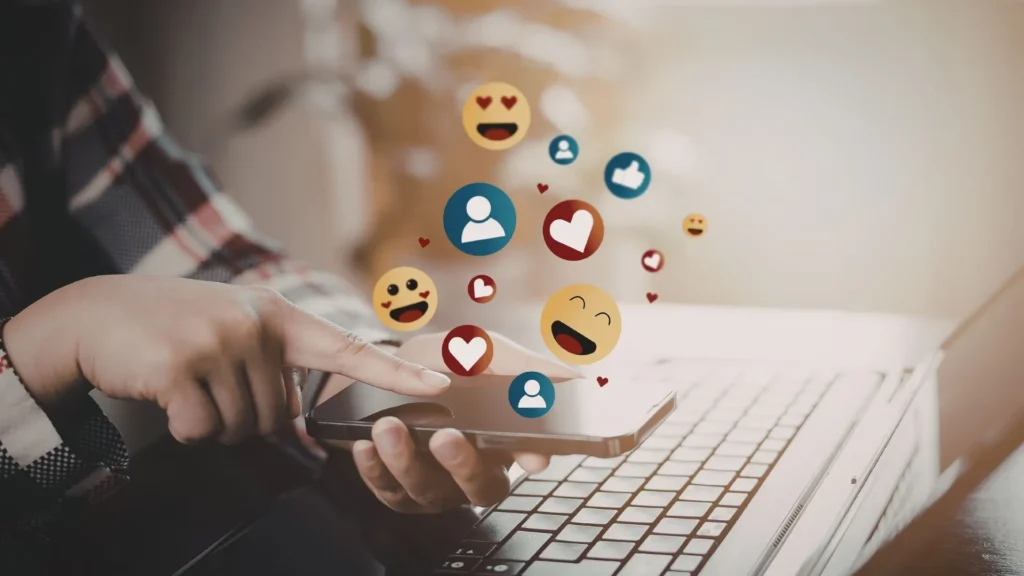 een hand die een smartphone vastheeft met likes, emoji's en hartjes 