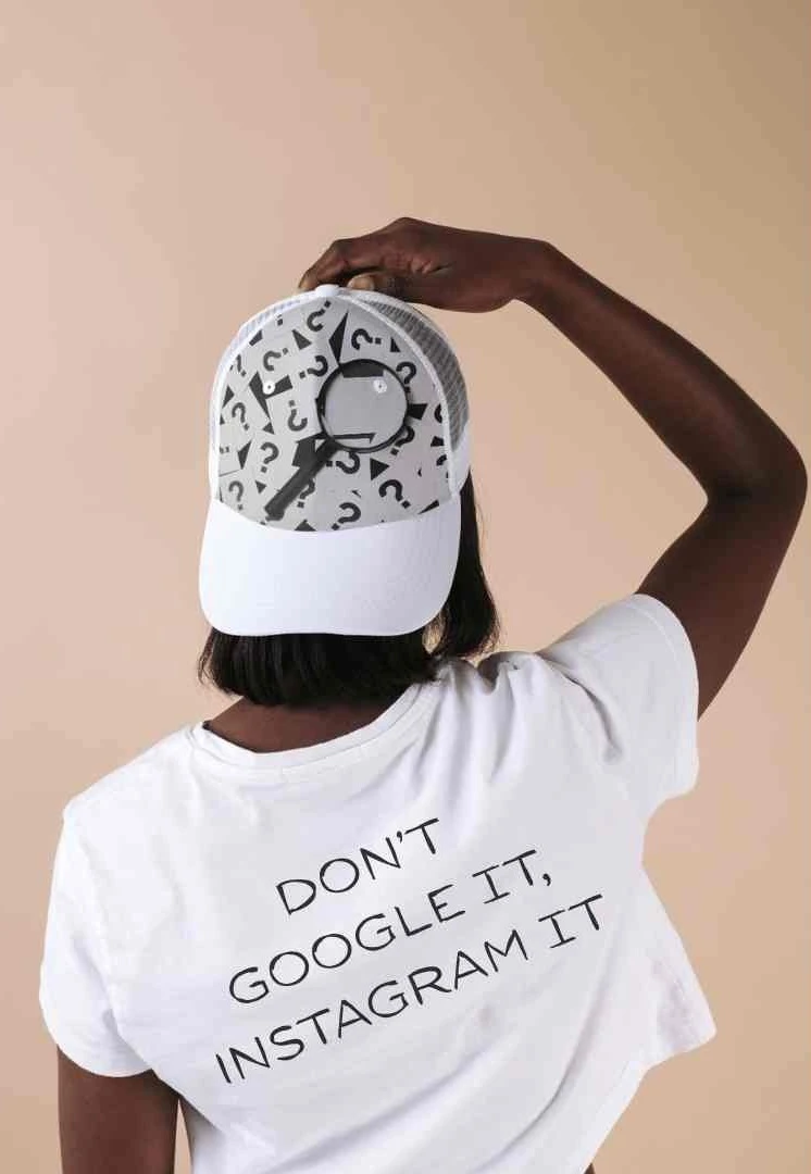feen vrouw poseert met haar rug naar de camera en houdt haar hand op haar pet, op haar rug staat een tekst over Google en social search
